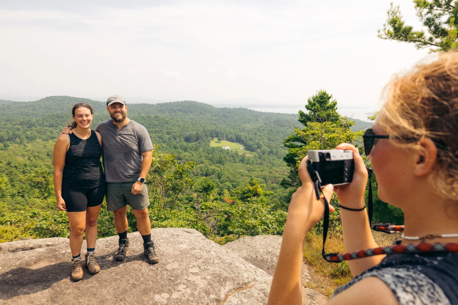 A man and woman pose for a picture on top of a mountain. 